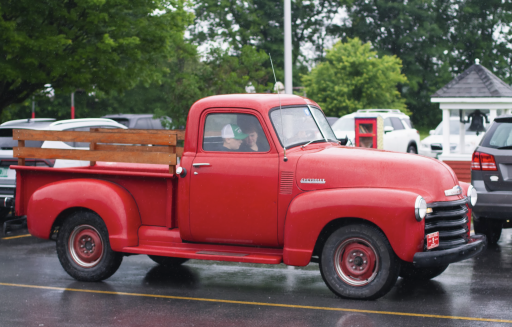A bright red vintage pickup truck arrives at Castleton Elementary School on a rainy morning for the last day of school.