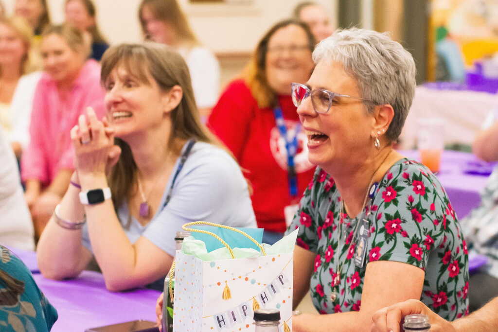 Tina Rampone laughs alongside colleagues while seated at a decorated table during her retirement gathering at Castleton Elementary School.