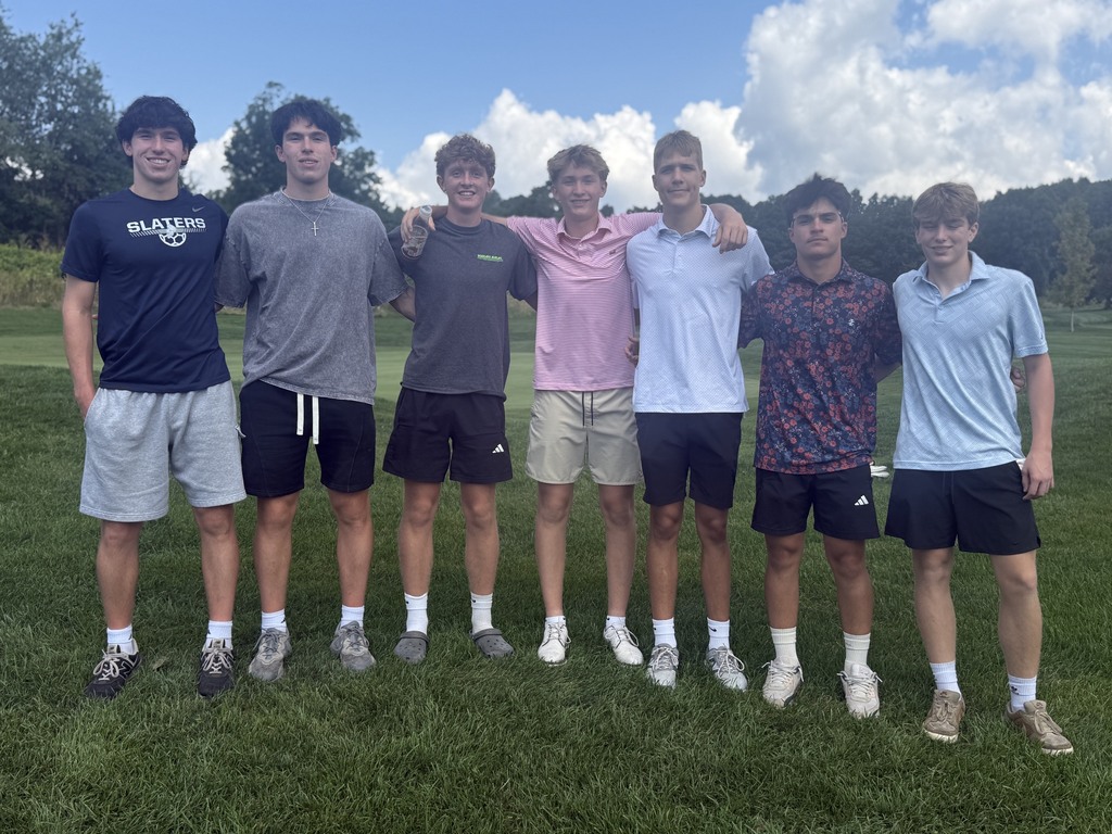 Seven students stand together with their arms around one another on the golf course during the Senior Class Golf Fundraiser, with green fairways and a blue, cloud-filled sky behind them.