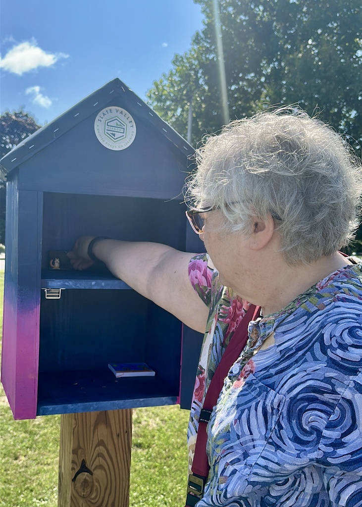 A community member places a small piece of artwork inside the newly opened Slate Valley Community Mini Art Gallery.