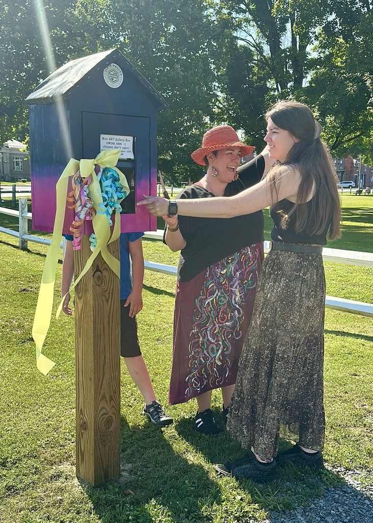 Two Slate Valley art teachers celebrate beside the Mini Art Gallery during its ribbon-cutting ceremony in Fair Haven Park.