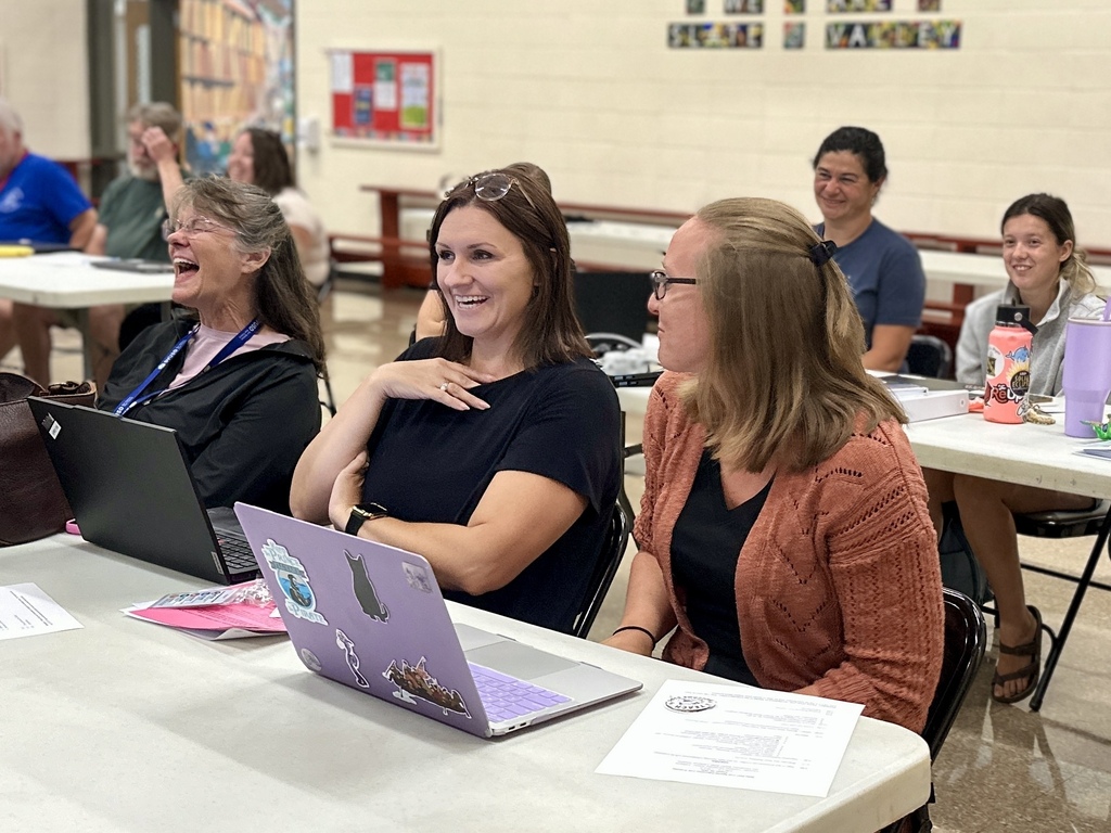 Three Slate Valley educators smile and laugh together during a special education inservice at Castleton Elementary School.