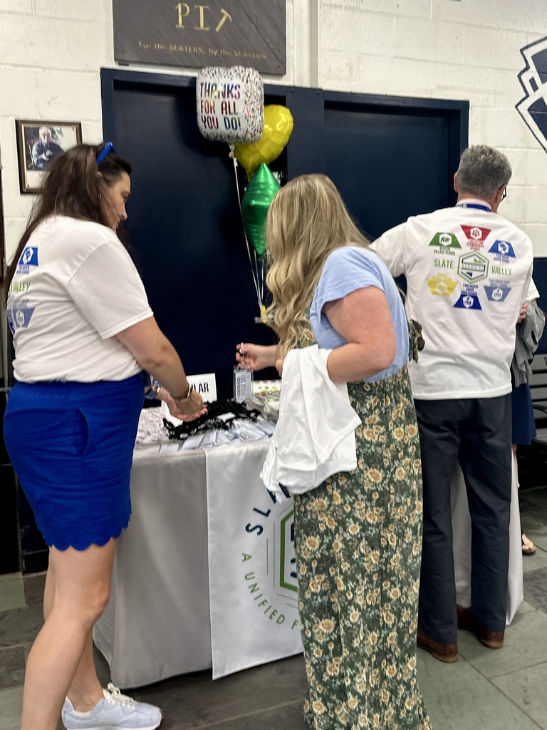 Slate Valley faculty and staff visit the district swag table to pick up Opening Day items, with colorful thank-you balloons displayed nearby.