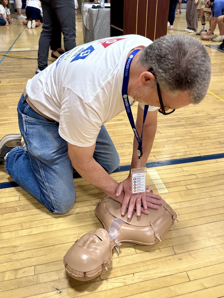Three Slate Valley staff members practice hands-only CPR on a training mannequin during the Opening Day Inservice.