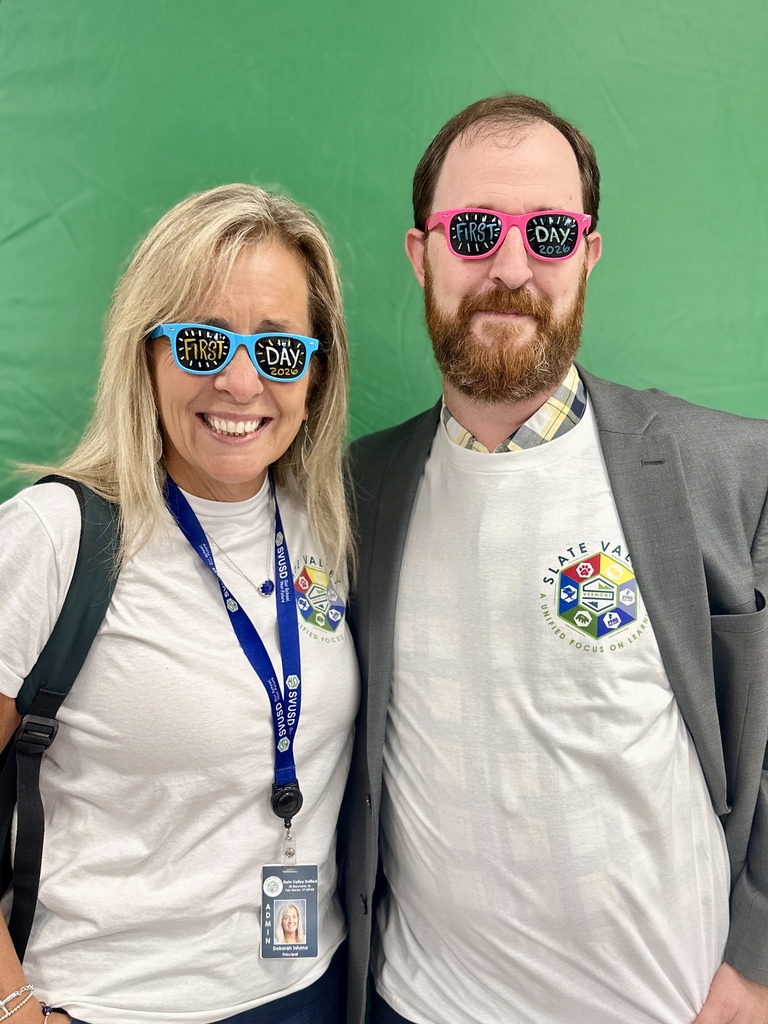 Two Slate Valley staff members smile together in “First Day 2026” glasses and matching district shirts at the Opening Day photo booth.