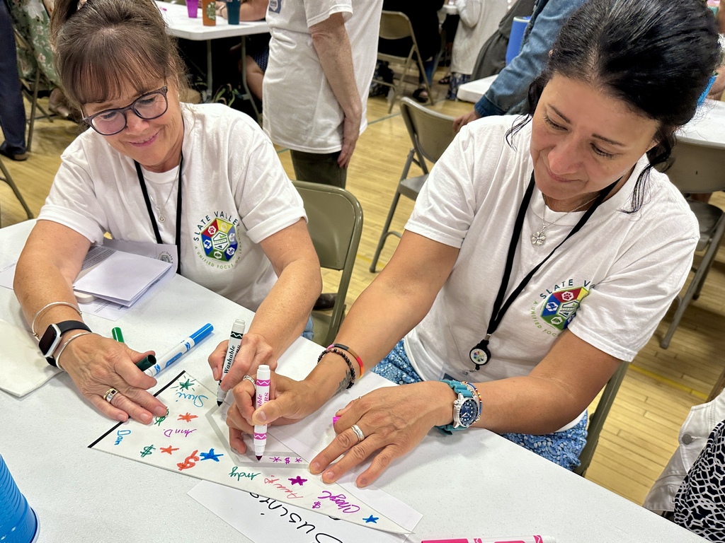 Two Slate Valley staff members add colorful names, symbols, and designs to their team pennant during the Opening Day activity.