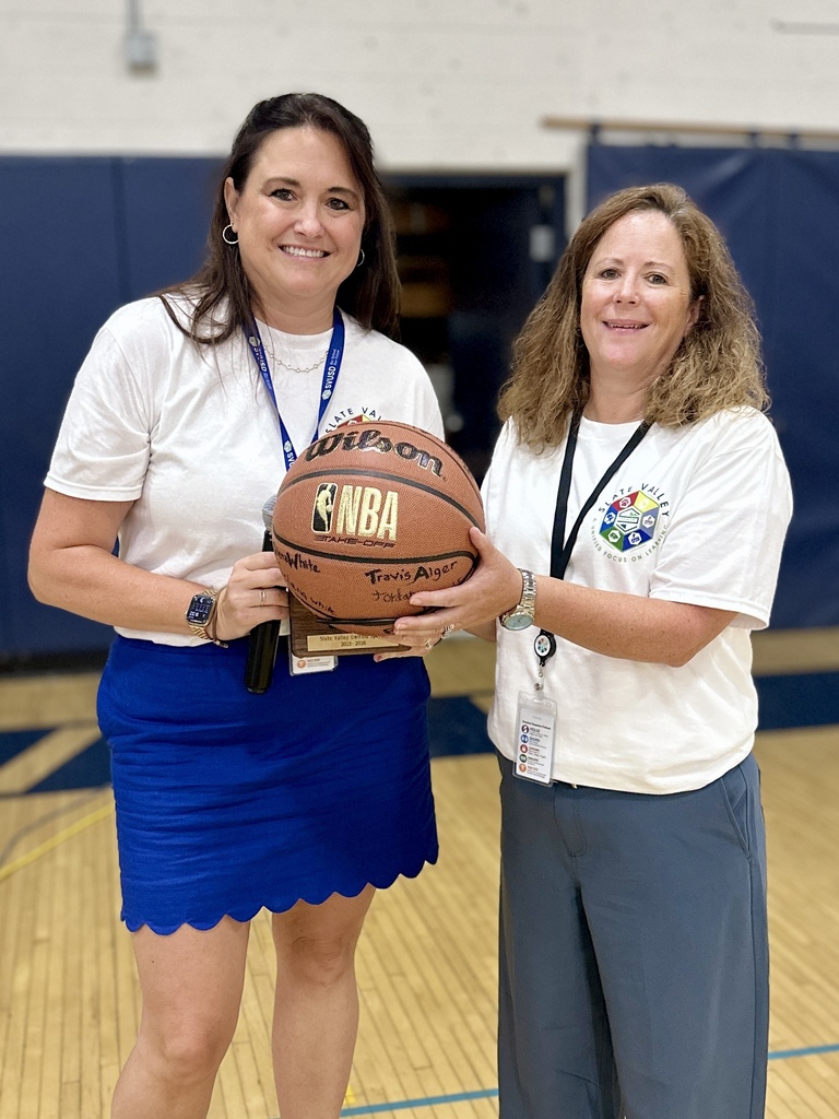 Superintendent Brooke Olsen-Farrell and Margaret Hayward smile while holding a commemorative basketball recognizing Slate Valley Unified Sports.