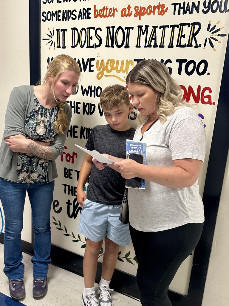 A student and family members review a schedule together in a hallway during Open House.