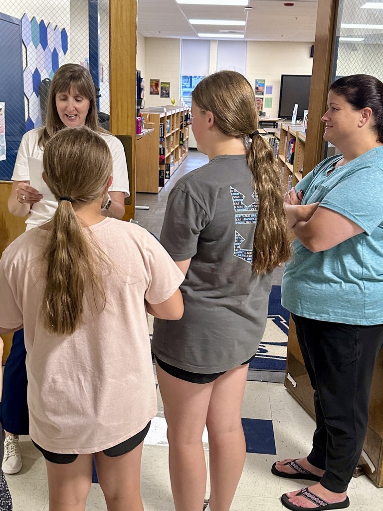 Students speak with staff members outside a classroom while touring the school during Middle School Open House.