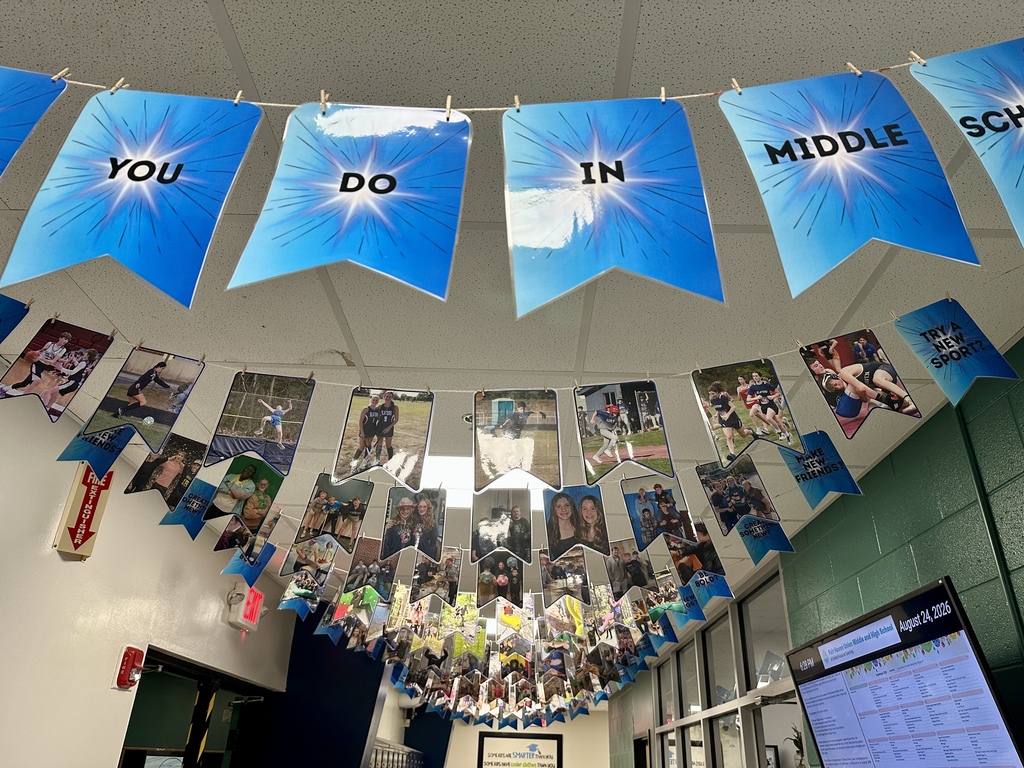 Blue pennants featuring photos of middle school activities and student life hang from the ceiling in a Fair Haven Union hallway.