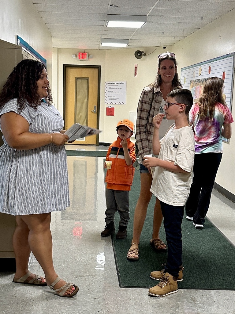 A CES staff member welcomes a family in the school hallway during Open House.