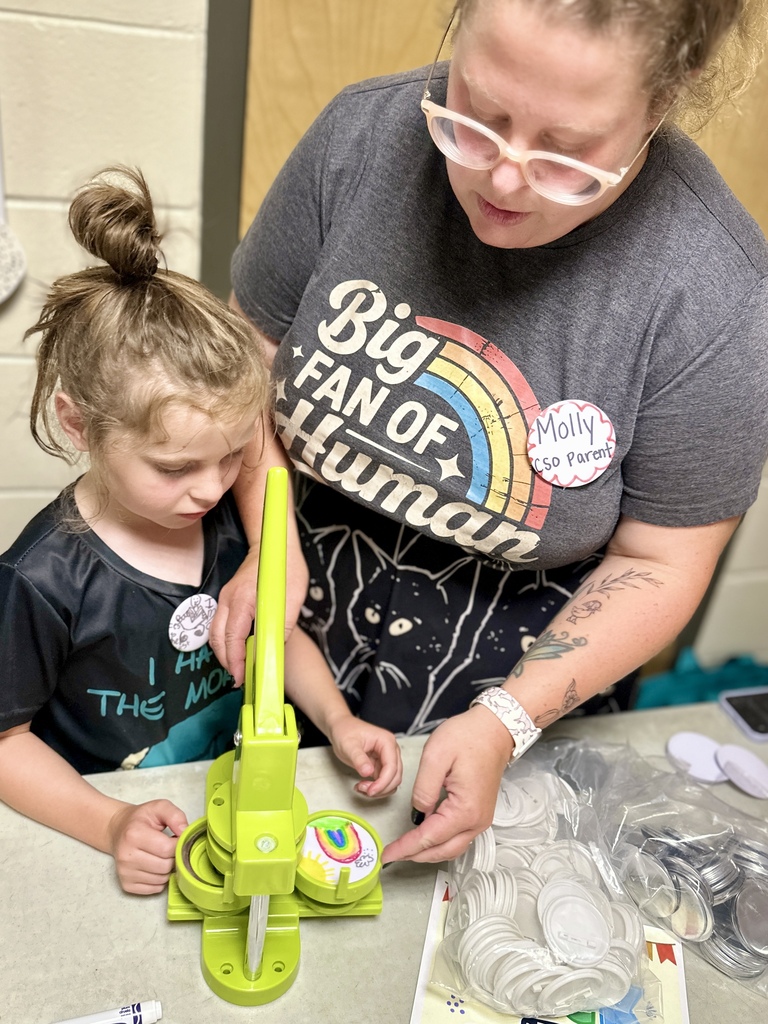 A CES student and parent work together to create a colorful button during an Open House activity.