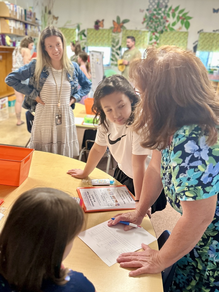 FHGS student and family members visit with a teacher and complete activities in a classroom.