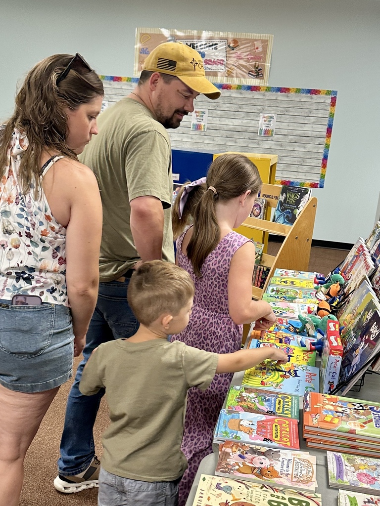 Students and family members browse books displayed at the FHGS Book Fair in the library.