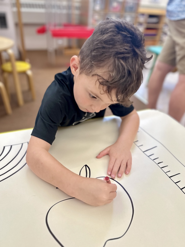 Young FHGS student colors a large classroom activity sheet during Open House.