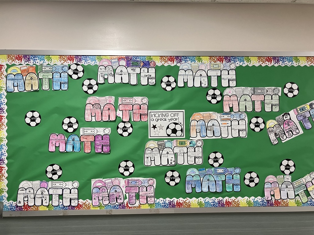 A green bulletin board titled "KICKING OFF a great year!" featuring student math art projects and paper soccer balls with names on them.