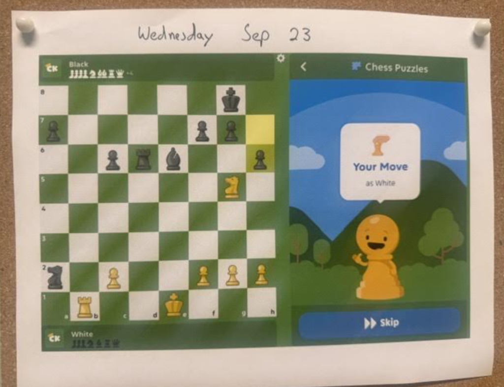 A printed Chess.com Kids puzzle interface pinned to a board, dated "Wednesday Sep 23," showing a chess board setup with the prompt "Your Move as White."