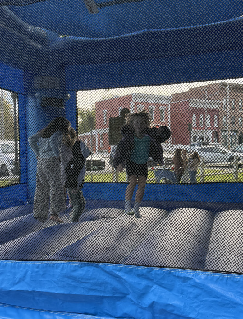 Children bounce and play inside a blue inflatable bounce house.