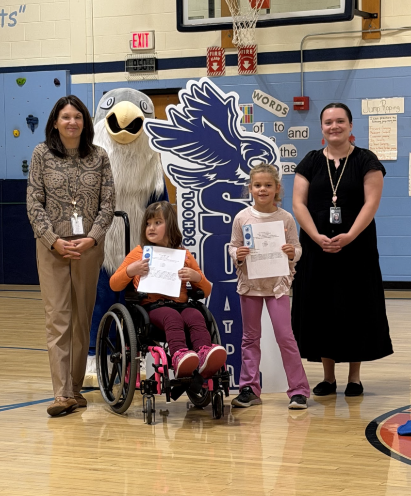 A student in a wheelchair and another student hold certificate papers while posing with two staff members and the falcon mascot.
