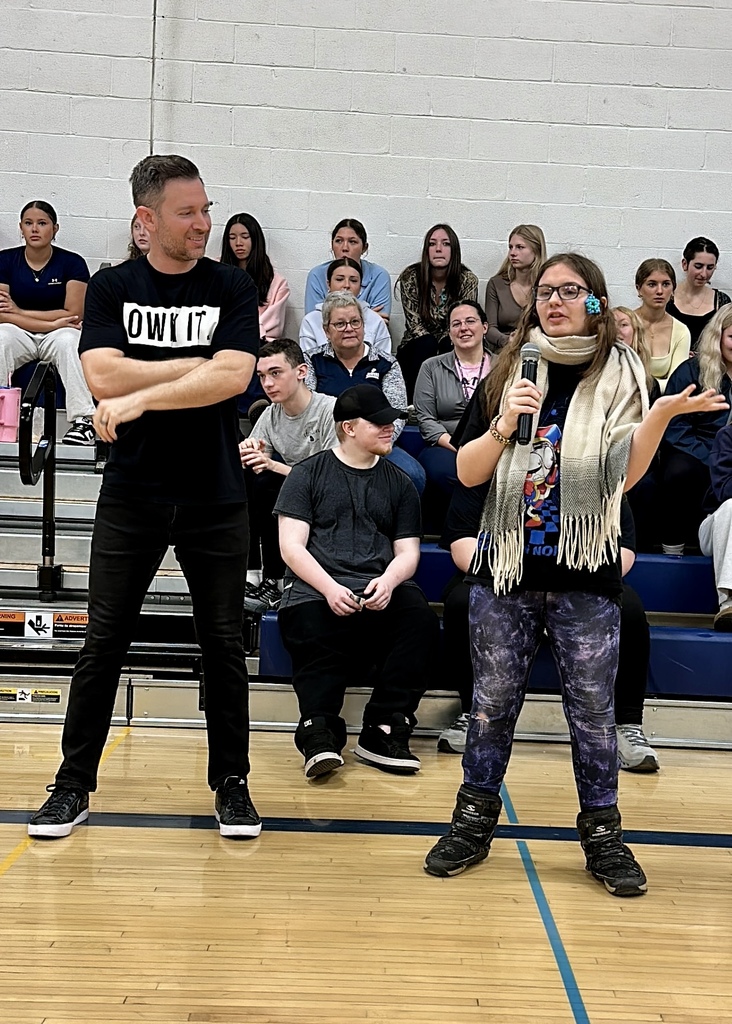 A female student wearing a scarf and galaxy leggings speaking into a microphone with Brandon Lee White standing nearby.