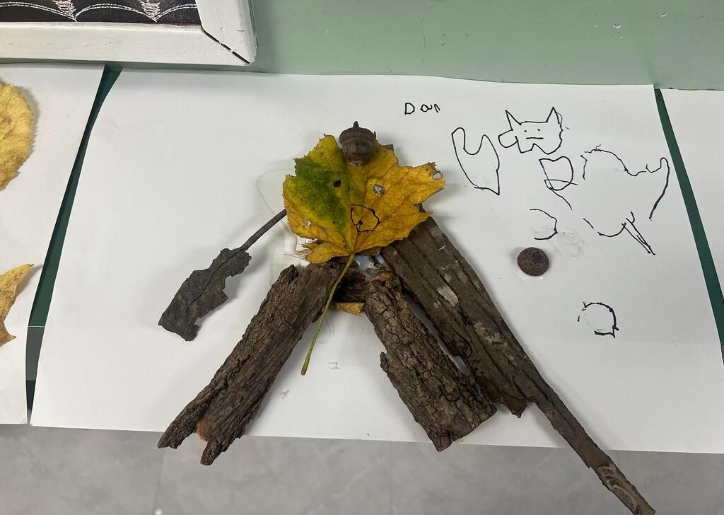 Student artwork titled "Dom," combining thick bark pieces, a yellow leaf, an acorn, and line drawings.