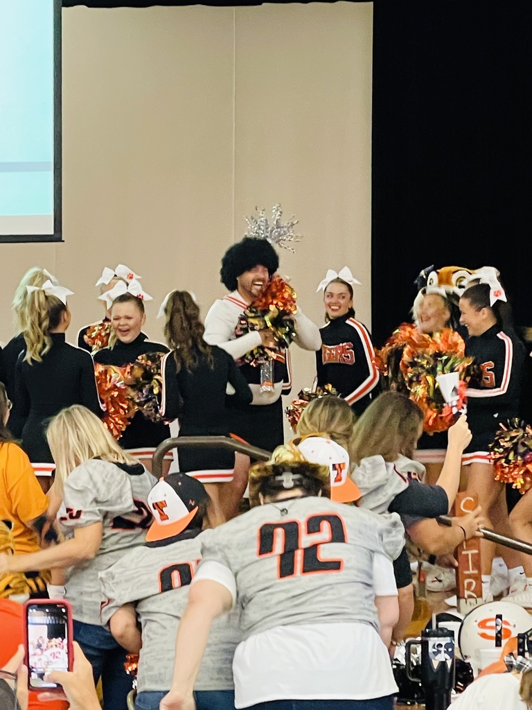 Coach dressed as cheerleader with spirit stick