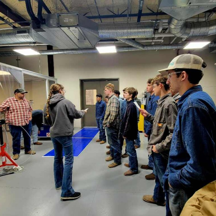 students talking to welder