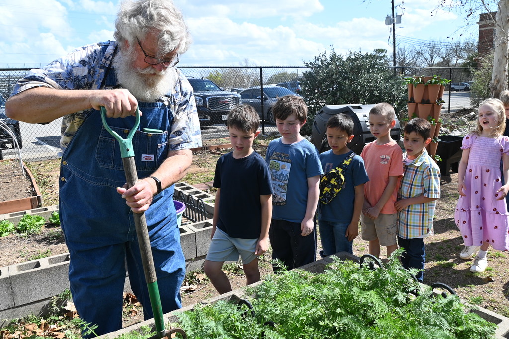 students and gardener digging in garden