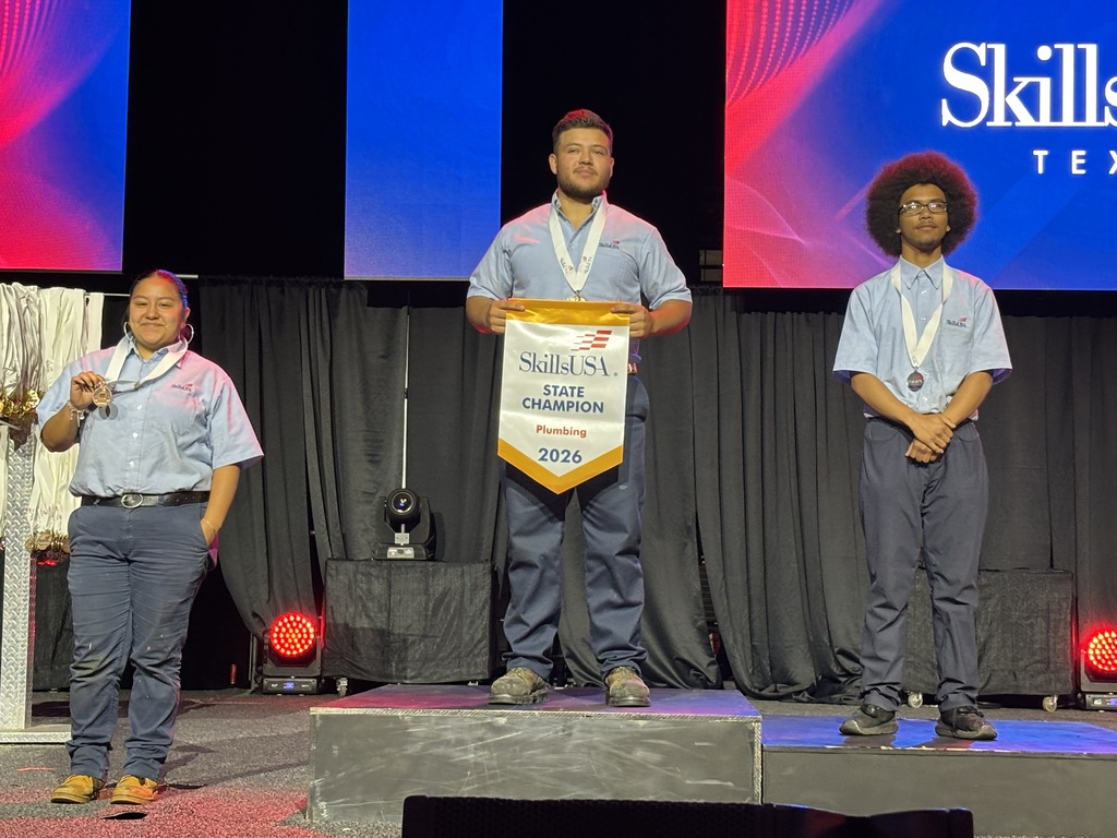 three guys standing on a podium.  The middle one holds a State Champion banner.