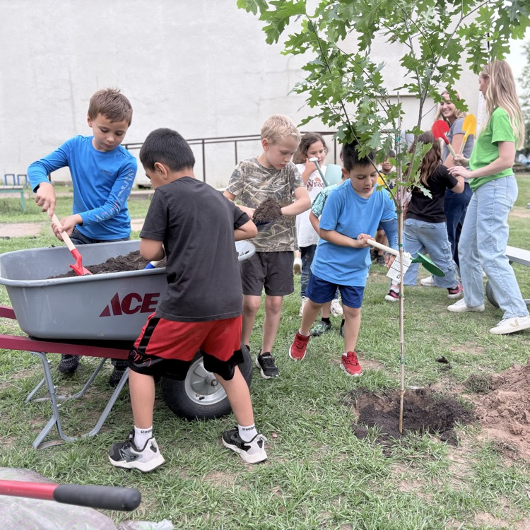 students digging dirt out of a wheel barrow