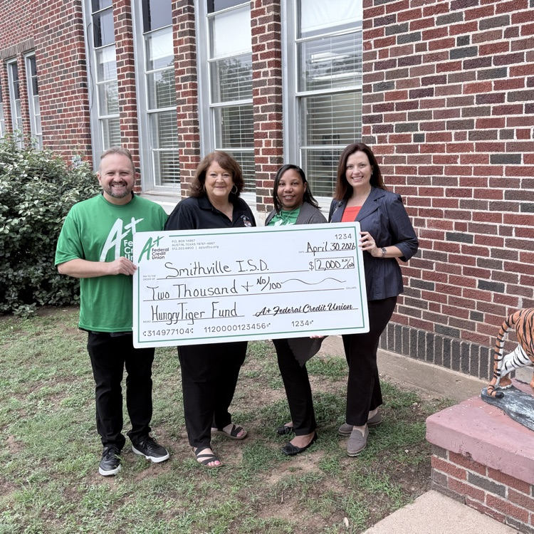 four adults stand holding a large check