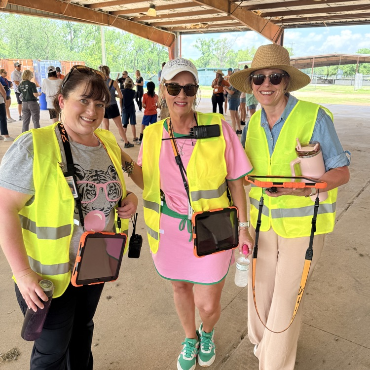 three women in bright green vests stand outside 