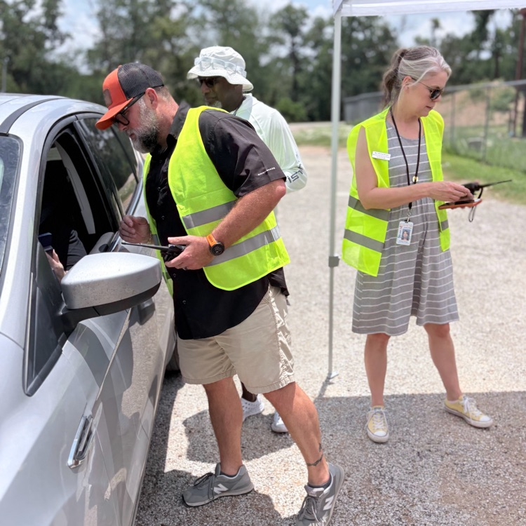 a man in a yellow vest stands at a car