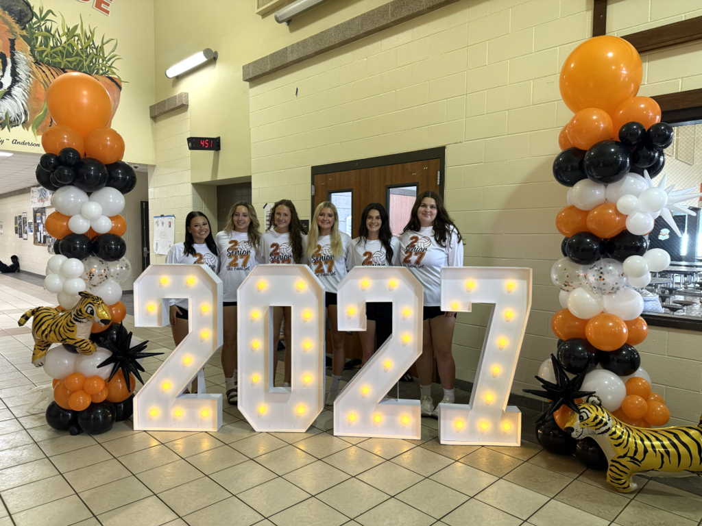 a group of students stand behind large 2027 light-up numbers