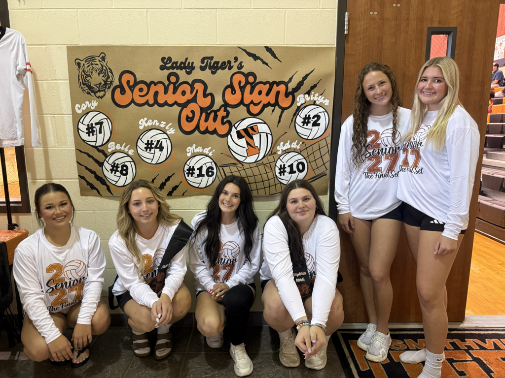 a group of students gather around a sign that says "senior sign out" with volleyballs on it.
