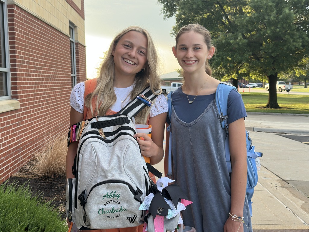 Two high school girls pose in front of the school 