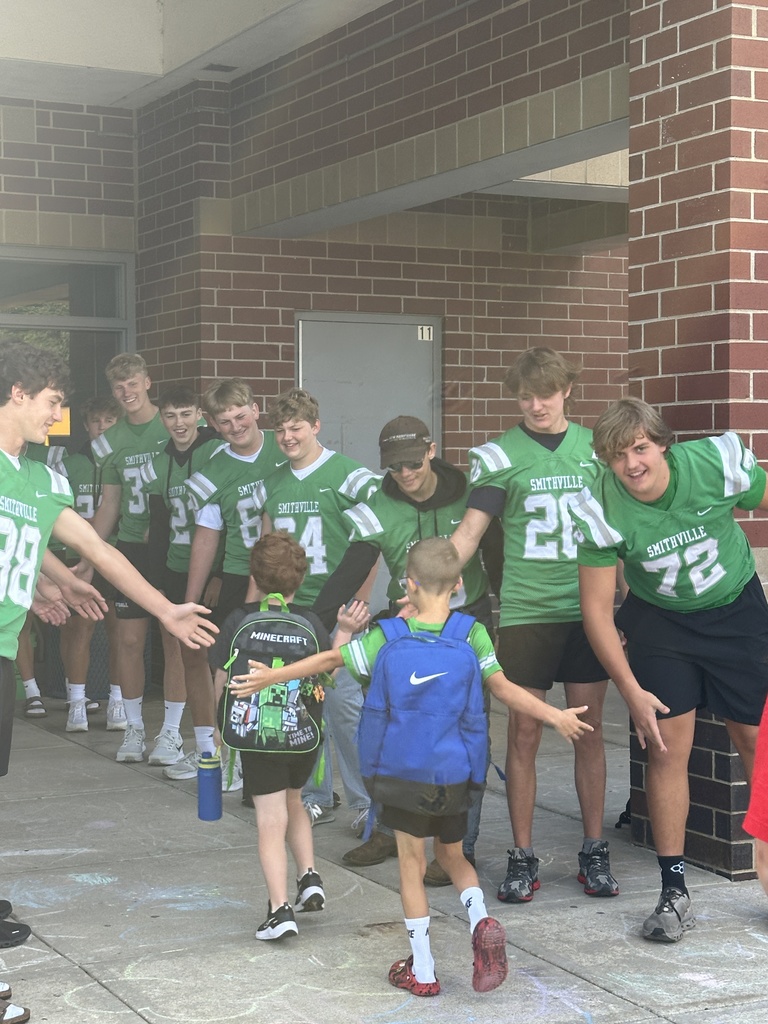 Football players line up in front of the school to greet elementary students