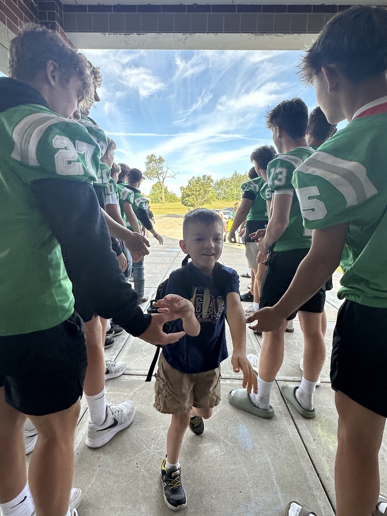 Football players line up in front of the school to greet elementary students