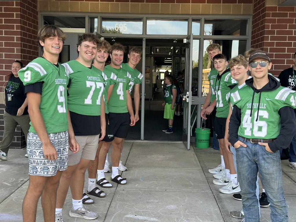 Football players line up in front of the school to greet elementary students