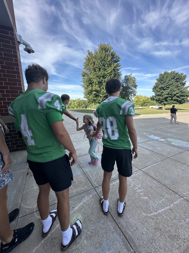 Football players line up in front of the school to greet elementary students