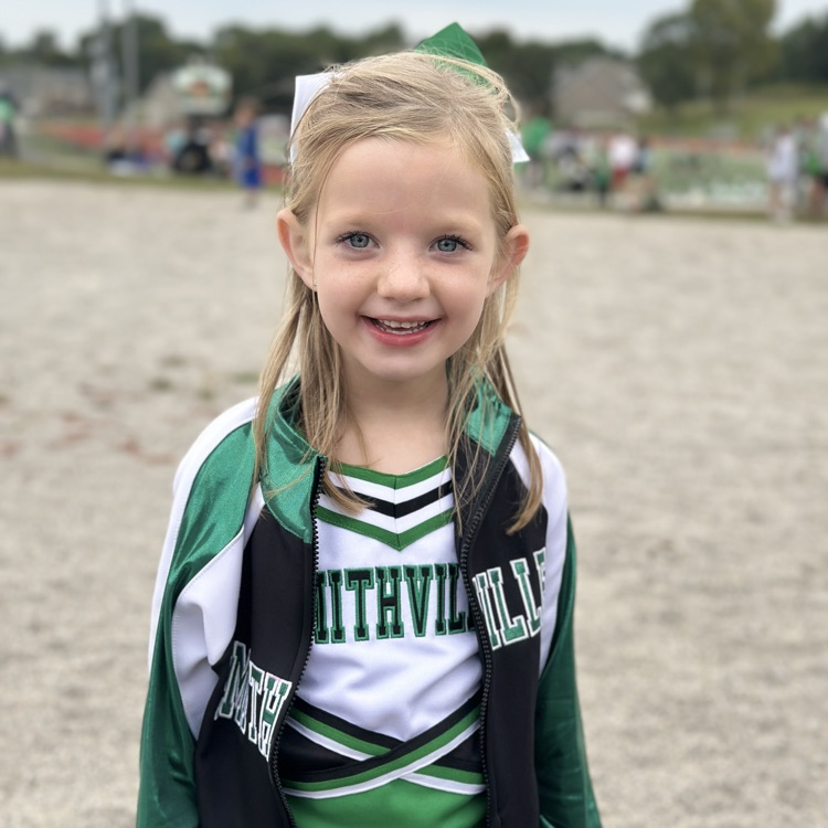 Little girl in a cheer uniform, smiling at the camera