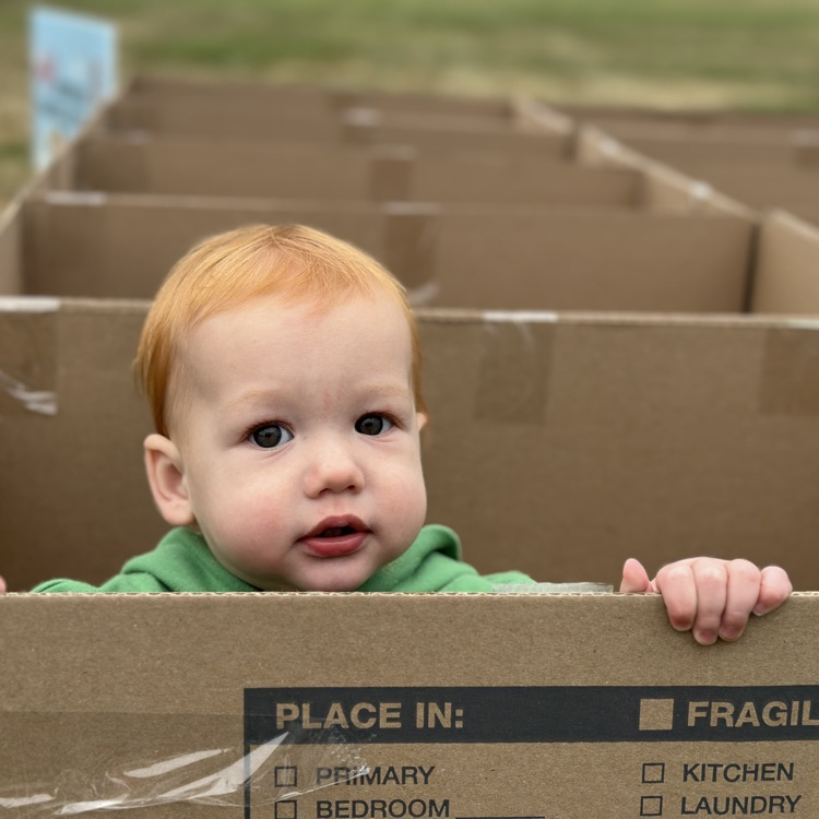 A baby playing in the box maze at the tailgate
