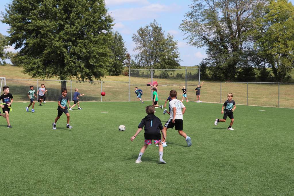 Boys playing kickball and soccer on the new turf area of the playground