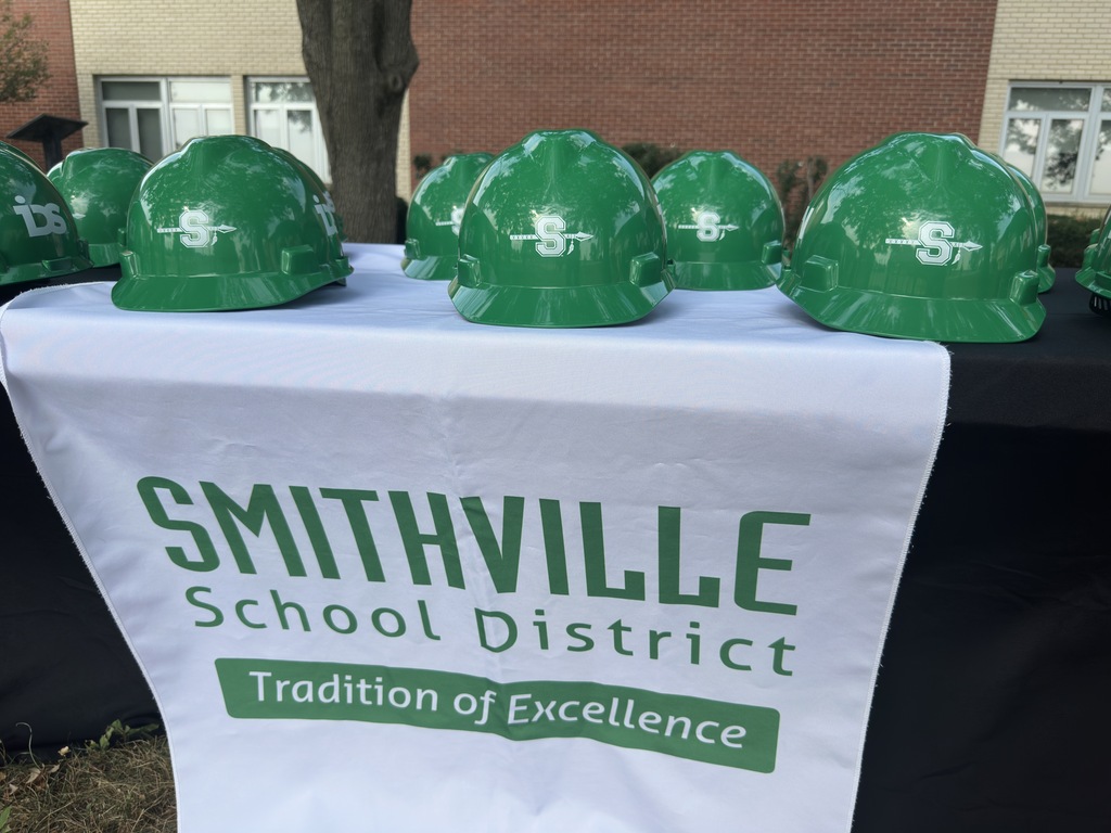 Green hard hats on a table with the Smithville School District Logo