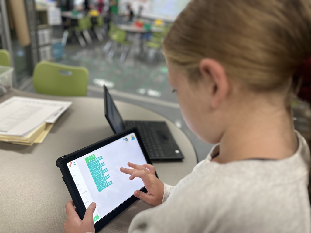 6th Grade student works on tablet to code a robot to pick up trash