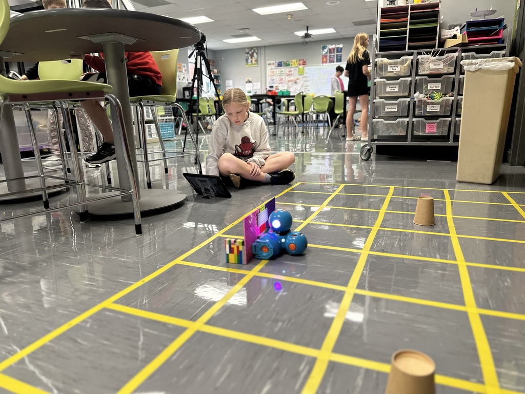 6th Grade student works on tablet to code a robot to pick up trash