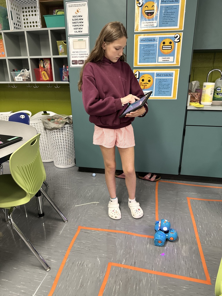 6th Grade student works a tablet to code a robot through a maze