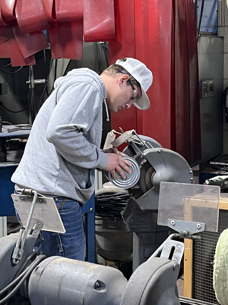 A student uses a grinder to smooth the surface of his tin can jack-o-lantern.