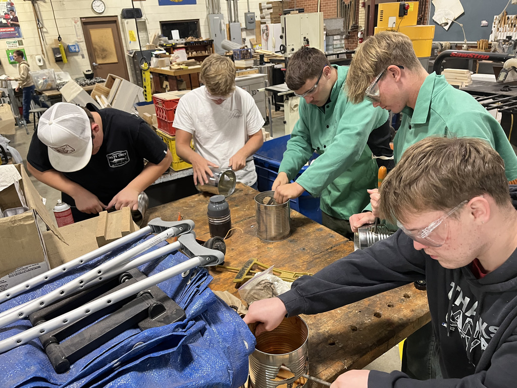 students work on cutting their tin cans into jack-o-lanterns.