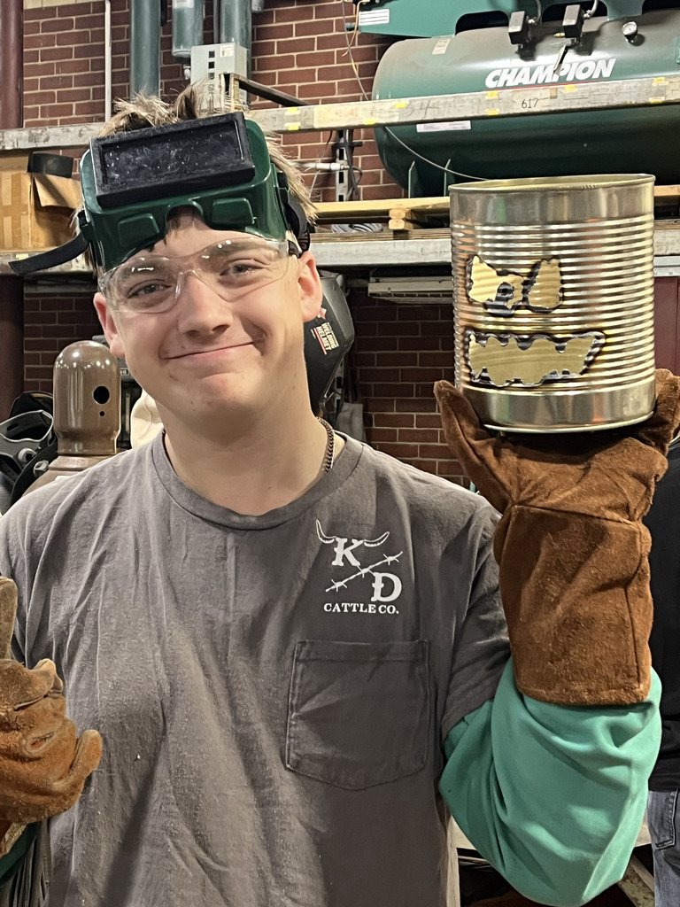 A student holds up his tin can after cutting his jack-o-lantern face.